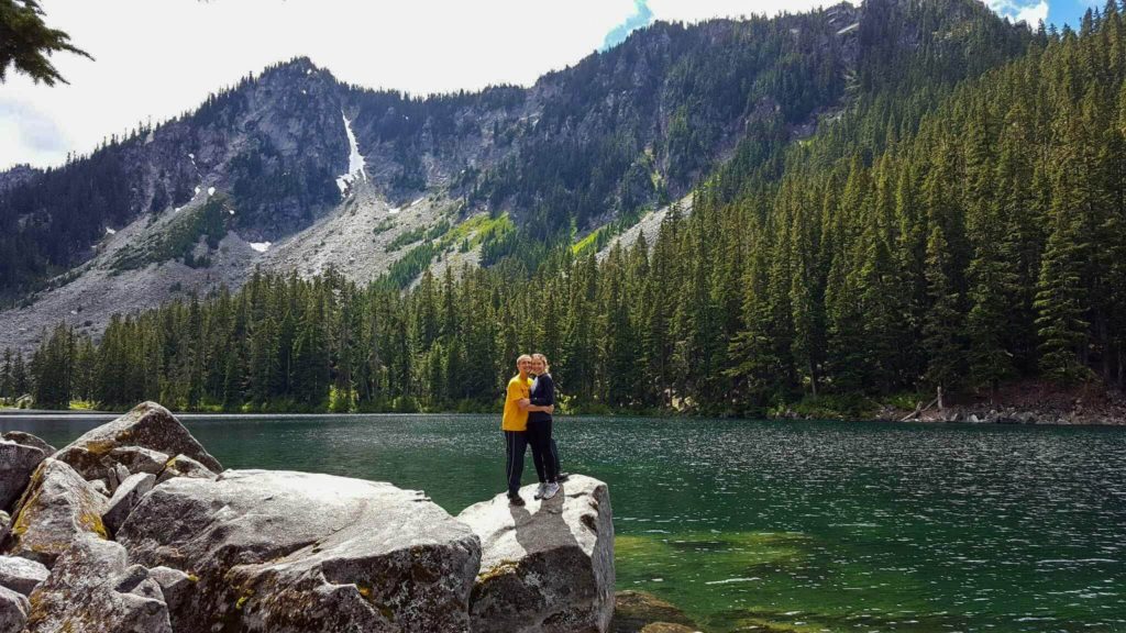 Two hikers embrace at Surprise Lake in Mount Baker-Snoqualmie National Forest, Washington