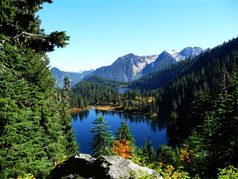 A blue lake surrounded by evergreen trees and mountain peaks