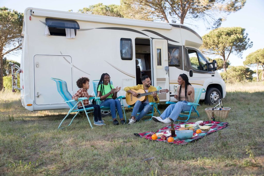 A family enjoying a picnic in front of a camper