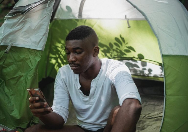 Man looking at his smartphone while sitting in a green and white tent