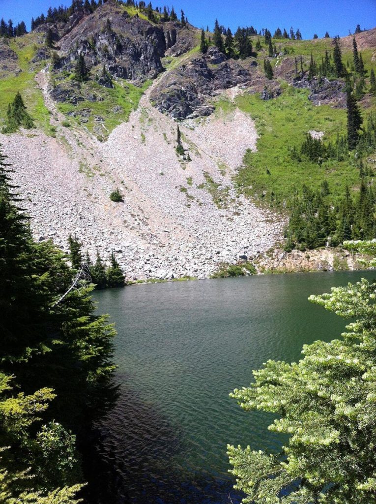 A green lake at the base of a mountain peak