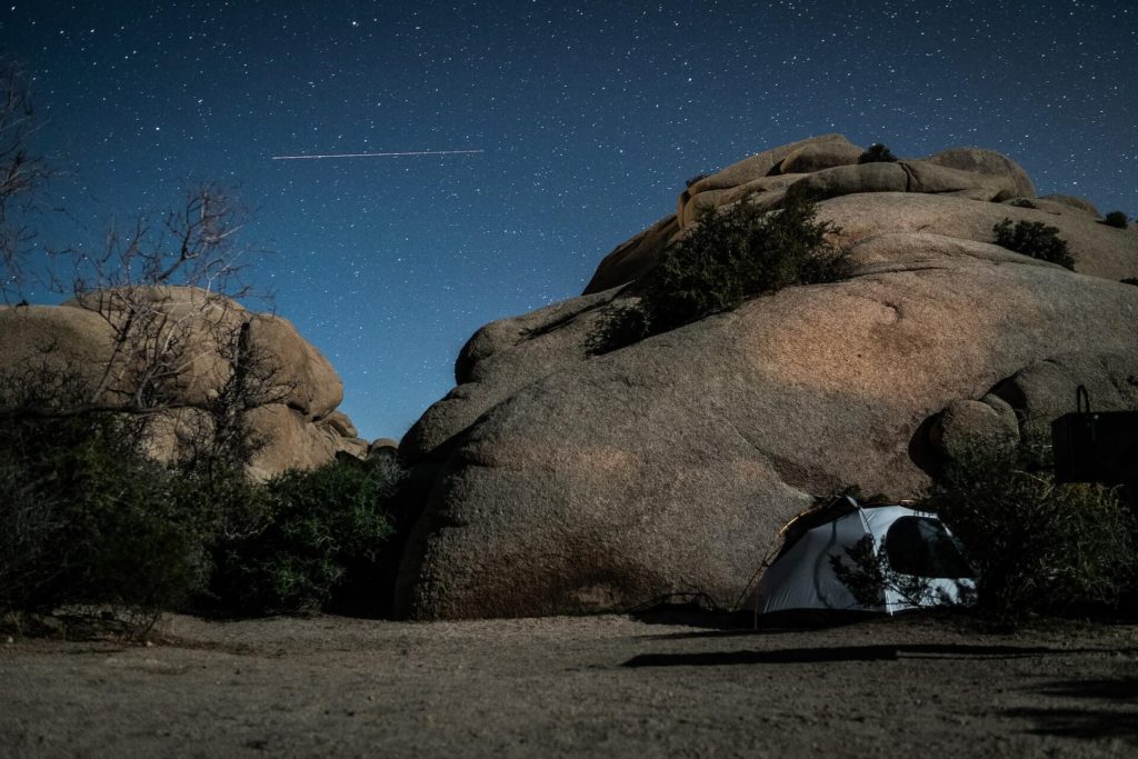 A tent in front of large boulders at night