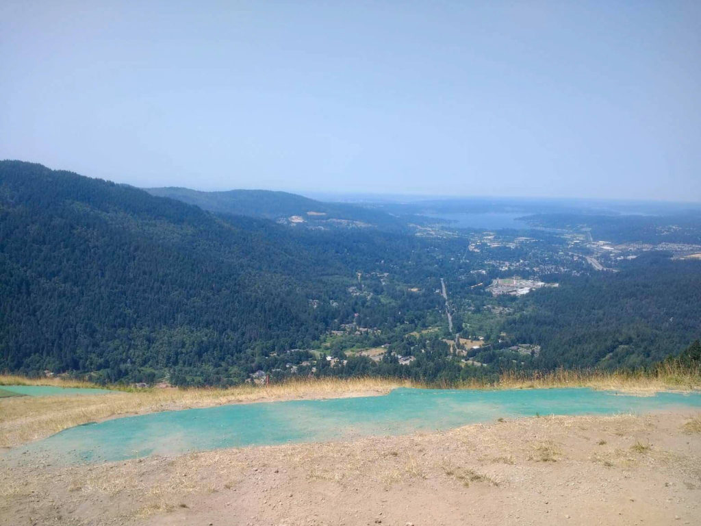 A green launch ramp in front of a city surrounded by mountains and a lake in the distance