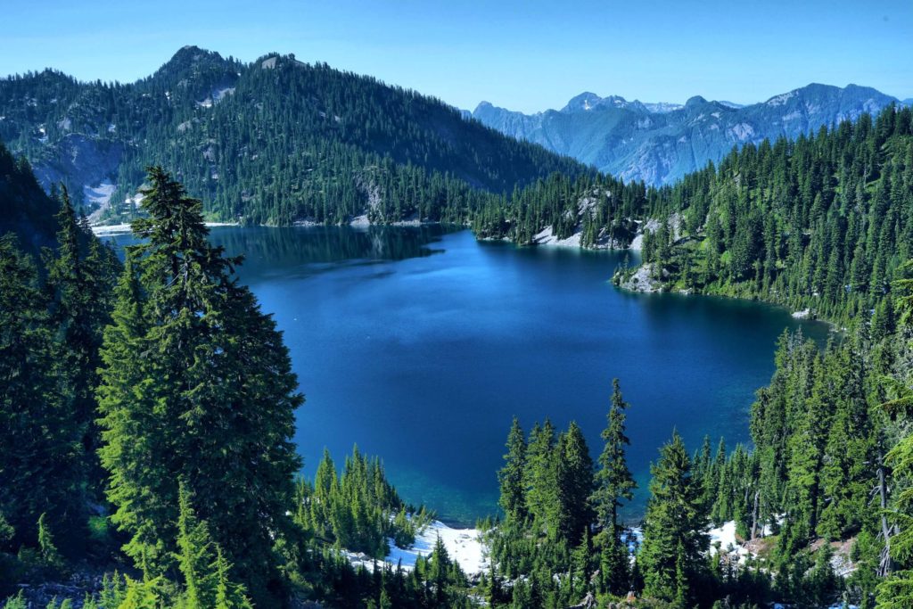 A blue lake surrounded by tree-covered mountains