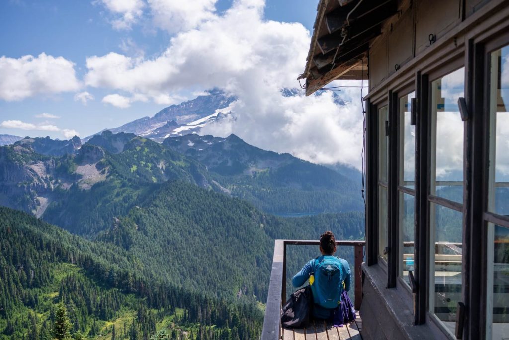 A woman sits at a lookout tower and looks at a mountain
