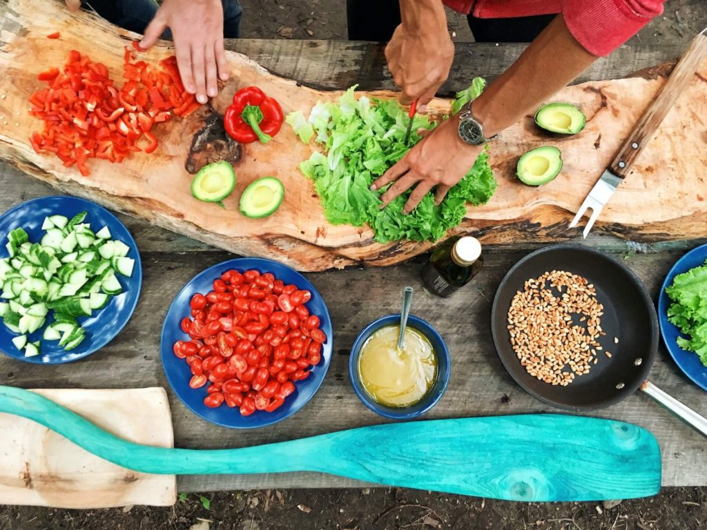 A bird's eye view of a campground picnic table covered in chopped vegetables