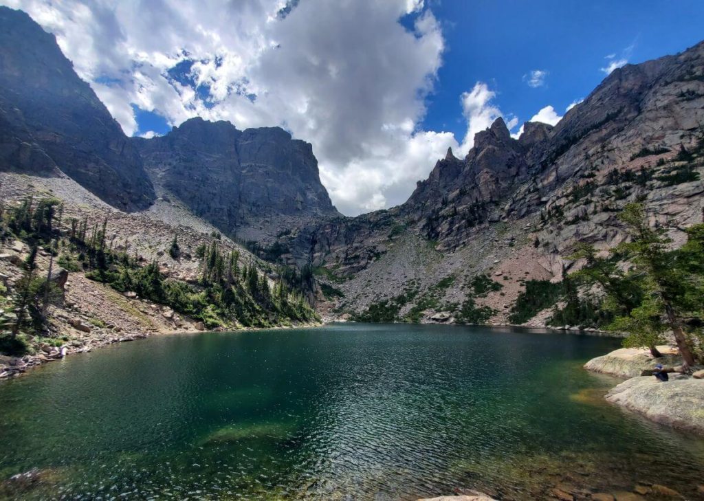 A green lake surrounded by jagged, rocky peaks. The beauty of Emerald Lake makes it one of the busiest hikes in Rocky Mountain National Park.