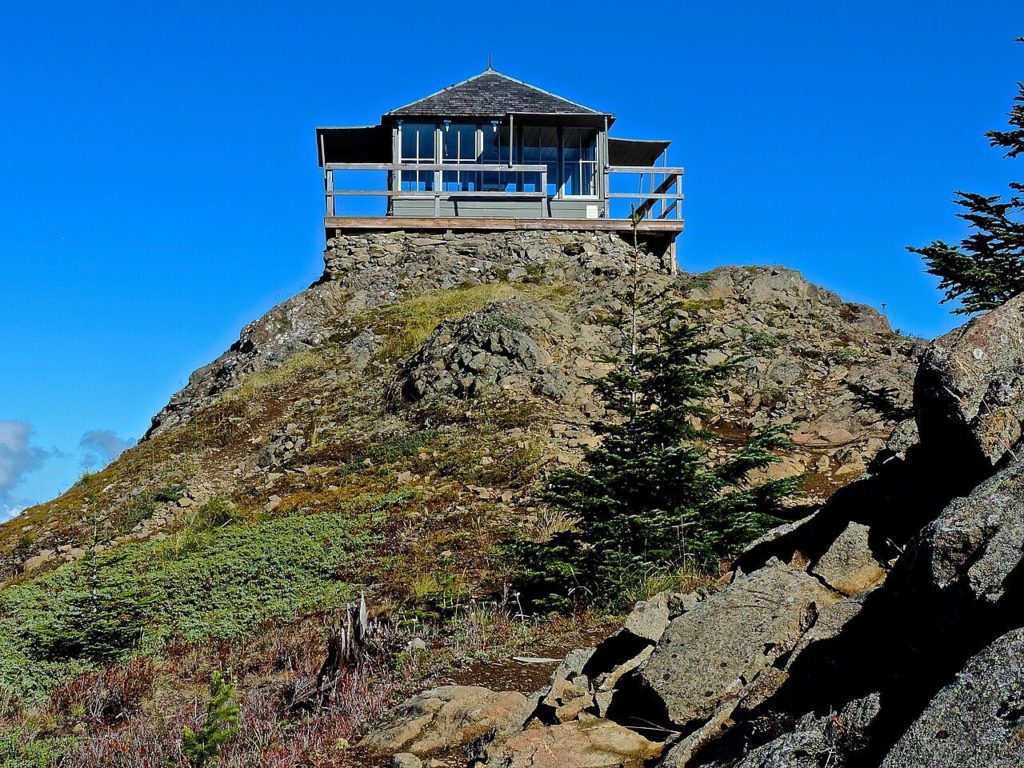 Kelly Butte Lookout stands atop a rocky hill under a clear blue sky