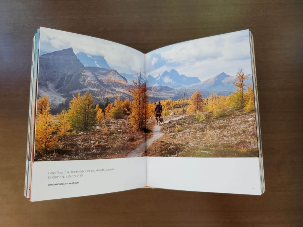 A book lays open on a coffee table to a page showing a hiker in Banff National Park