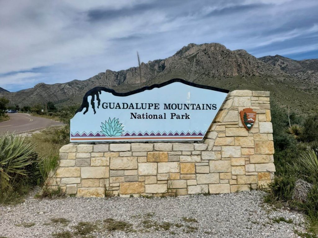 Guadalupe Mountains peek over the entrance sign to the Guadalupe Mountains National Park