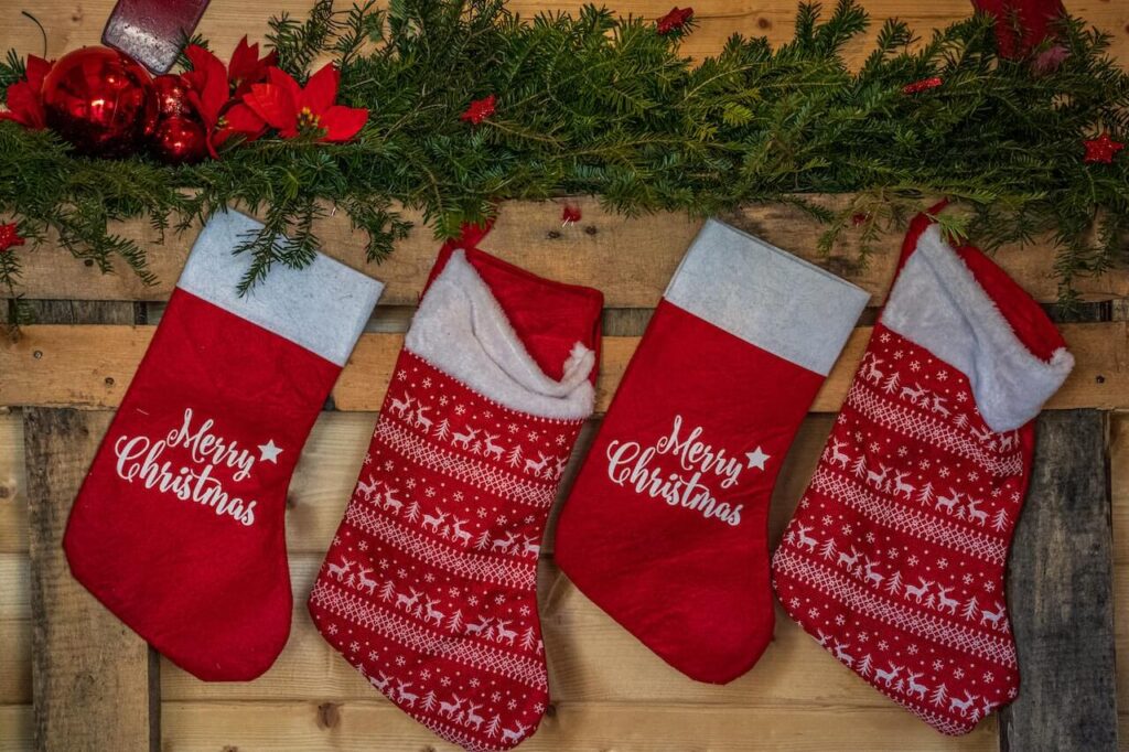 A row of four red stockings hang from a wooden fireplace mantle
