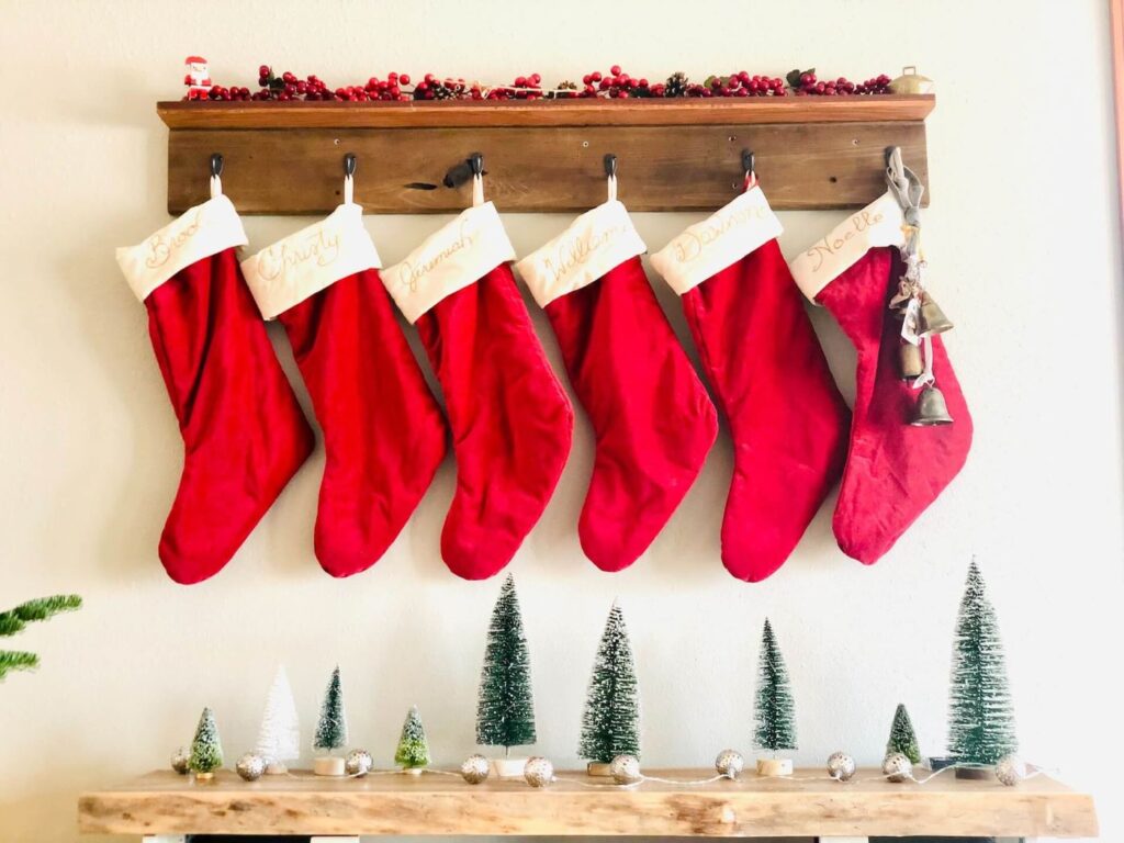 A row of red stockings hang from a row of wooden hooks